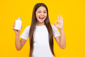 Staying healthy. Teenage girl holding vitamin pills on yellow isolated background. Excited teenager, glad amazed and overjoyed emotions.