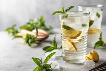Cold and refreshing detox water with lemon, mint and ice in glasses. Homemade lemonade or cocktail. Copy space