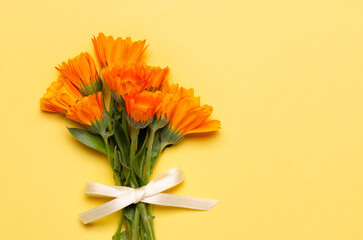 A bouquet of orange calendulas on yellow background with copy space. 