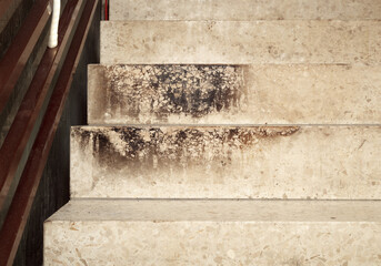 Terrazzo staircase with burn marks or soot after building fire. Composite stone stairs steps dirty...