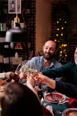People clinking glasses with sparkling wine, proposing christmas toast at festive dinner. Winter holiday celebration with parents, family gathering together, drinking at new year party