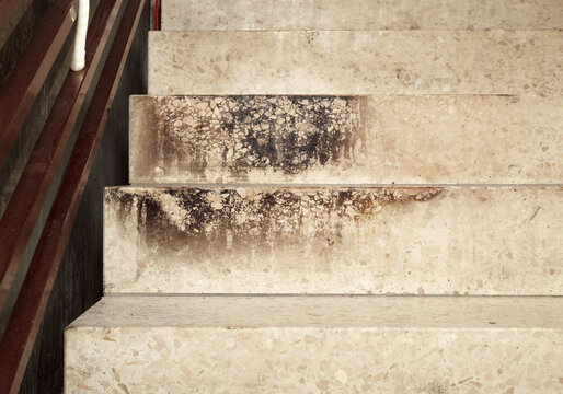 Terrazzo staircase with burn marks or soot after building fire. Composite stone stairs steps dirty and heavy signs of temperature. Selective focus.