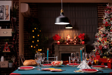 Christmas eve table in luxury interior, xmas holiday family dinner preparation, beautiful decorated place interior. Wine glasses, dining plates, empty tableware on tabletop