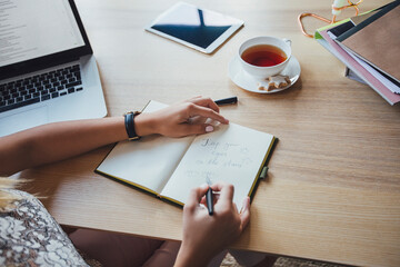 High angle view of businesswoman writing in diary while sitting at table
