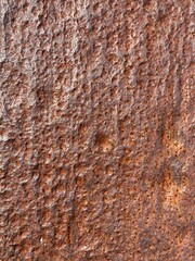 A brown, rusty metal surface with corrosion grooves