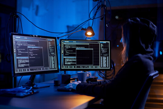 cybercrime, hacking and technology concept - female hacker in dark room writing code or using computer virus program for cyber attack