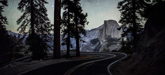 Road passing by silhouette trees in Yosemite National Park at night