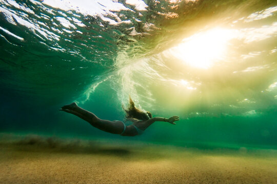 Side view of woman in bikini swimming underwater