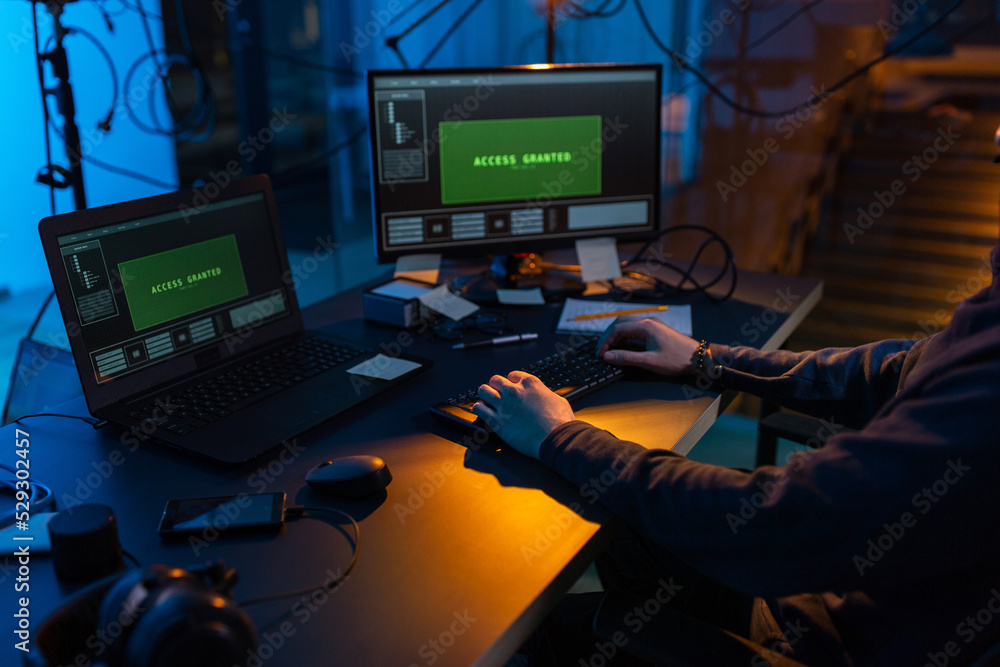 Poster cybercrime, hacking and technology concept - close up of male hacker in dark room writing code or us