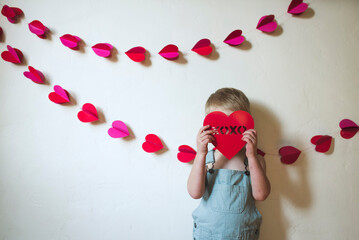 Boy hiding face with heart shape while standing against wall