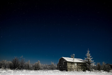House at snow covered field against clear sky at night