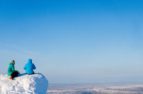 Friends sitting on mountain against clear sky