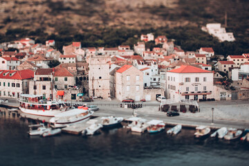 Tilt-shift image of boats moored at lake by houses in town