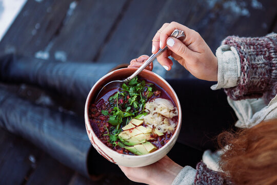 Midsection of woman holding food in bowl while sitting outdoors