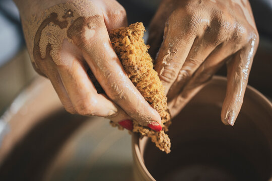 Cropped image of female potter scrubbing clay pot at workshop