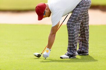 Man holding tee while playing at golf course