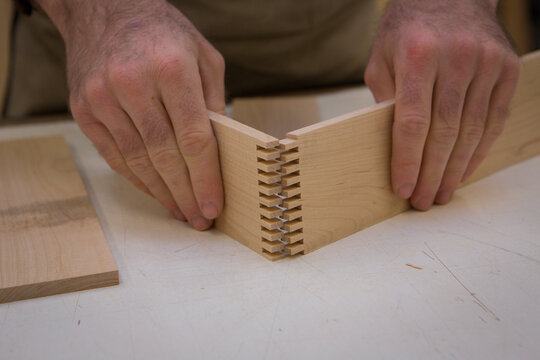 Midsection Of Carpenter Joining Wooden Planks At Table In Workshop