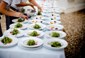 Workers serving salad in plates on table