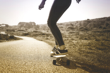 Low section of woman skateboarding on road against sky