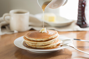 Cropped image of jug pouring honey on pancakes