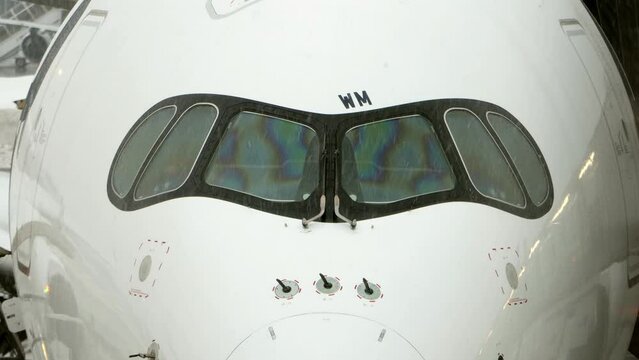 The cockpit of an airplane parked at a winter airport with falling snow