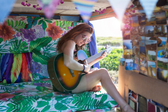 Woman playing guitar while sitting in motor home