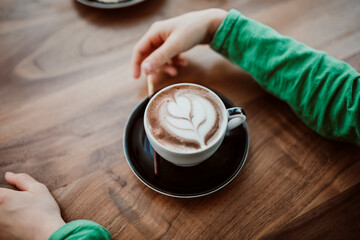 Cropped hands of boy with coffee at table in cafe