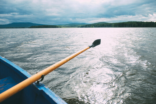 Oar in canoe on sea against cloudy sky