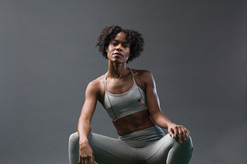 Portrait of confident woman wearing sports clothing while sitting against wall in gym