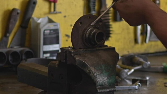 Master Removes Oring from Metal Piece on Workbench in Repair Shop Footage.