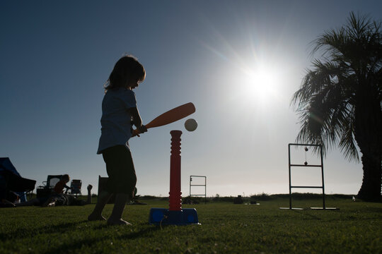 Side view of girl playing with t-ball at park during summer