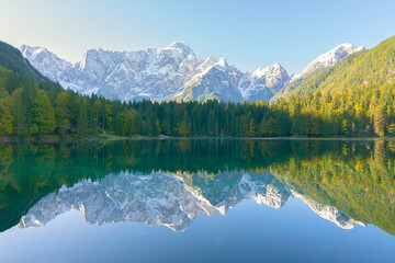 Symmetry view of lake by trees against mountain ranges during winter