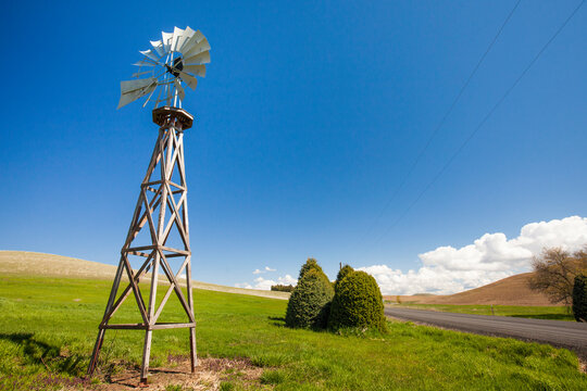 American-style windmill on hill against blue sky during sunny day