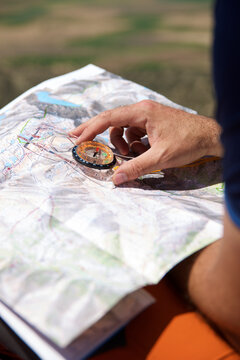 Cropped hands of hiker holding navigational compass with map