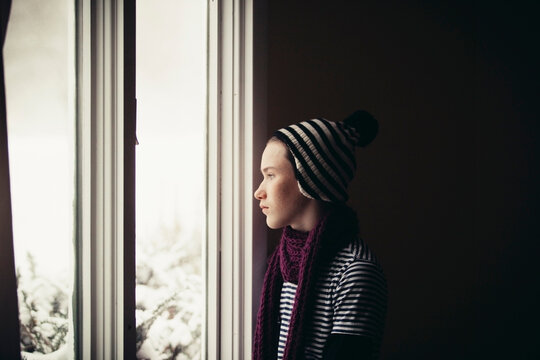 Thoughtful Teenage Boy Looking Through Window At Home