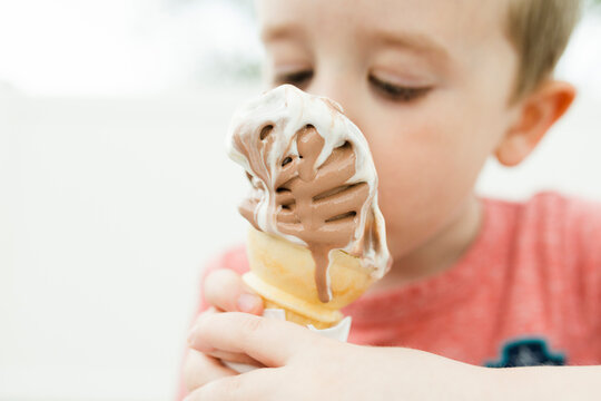 Close-up of cute boy eating ice cream cone while sitting outdoors