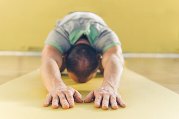 Young man bending while practicing yoga on exercise mat at gym