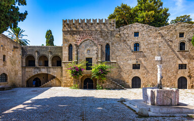Fototapeta premium Medieval arched street in the old town of Rhodes, Greece. Rhodes old town in Rhodes island in Greece. Historical streets of old town Rhodes with flowers in Rhodes, Dodecanese, Greece