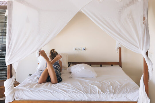 Rear view of young woman lying on bed at home