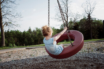 Rear view of playful girl swinging at playground