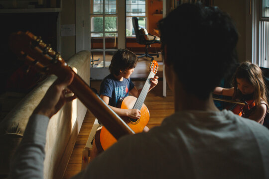 Father With Children Playing String Instruments While Sitting At Home