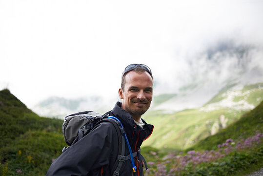 Portrait of confident smiling hiker with backpack standing against mountains