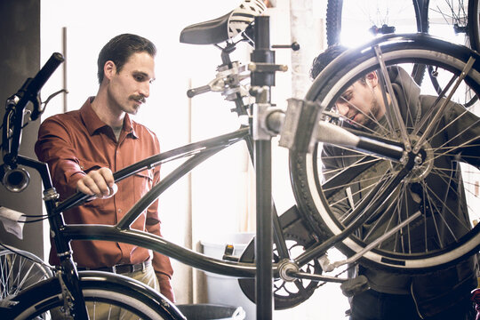Owner showing bicycle to male customer at workshop