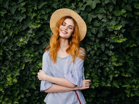 Woman with eyes closed wearing hat while standing against plants at park