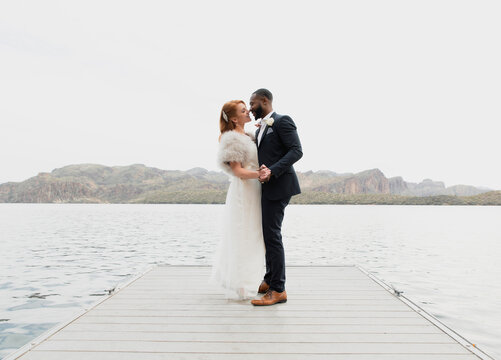 Side view of loving newlywed couple dancing on pier over lake against clear sky