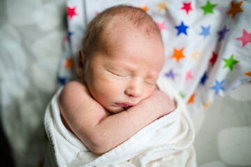 Overhead view of cute newborn baby boy sleeping on bed at home
