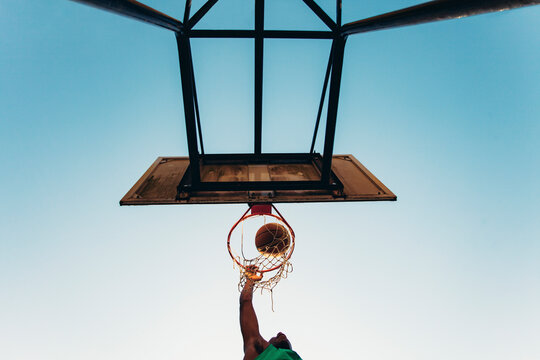 Low angle view of basketball player making basket against clear blue sky at court
