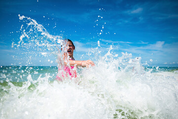Playful girl splashing water in sea against sky during sunny day