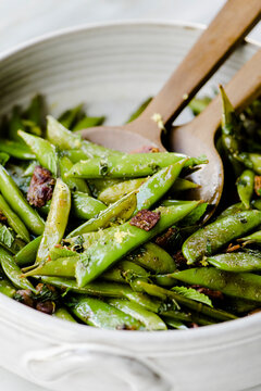 Close-up of fried pea pods with wooden spoons in container