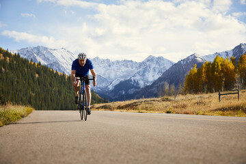 Full length of senior man riding bicycle on road against mountain range